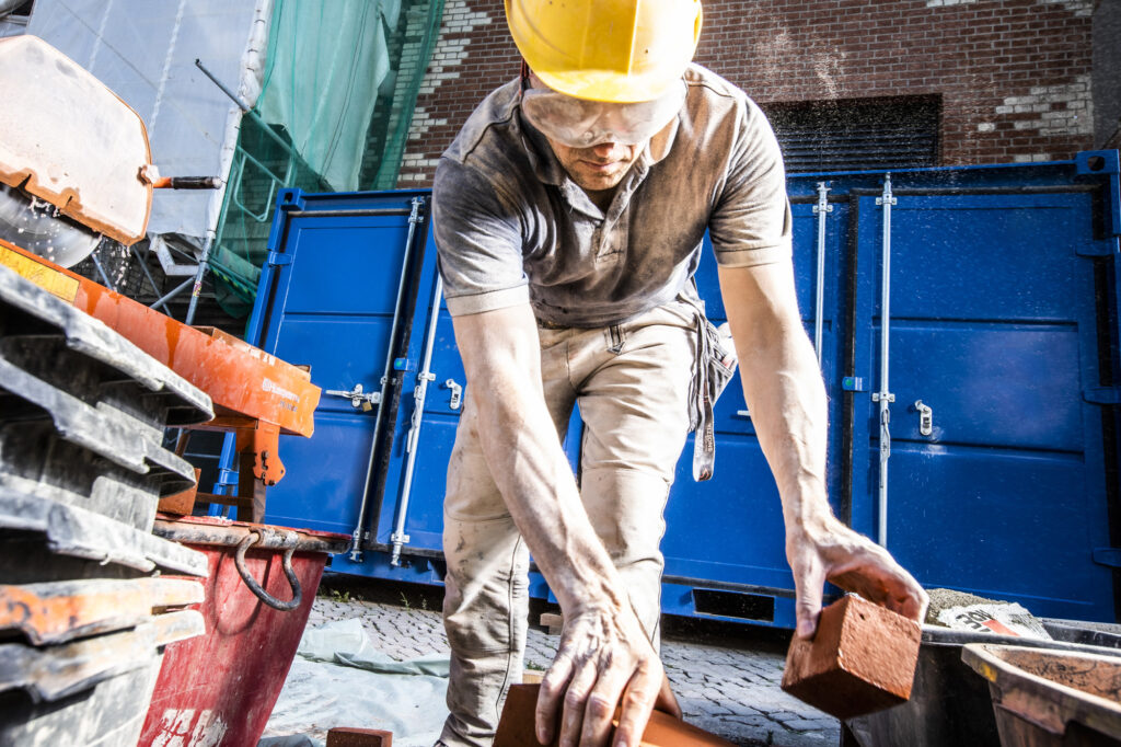 Ein Arbeiter mit Helm und Schutzbrille führt Baudienstleistungen auf einer Baustelle aus.
